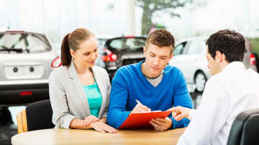 People signing dealership paperwork